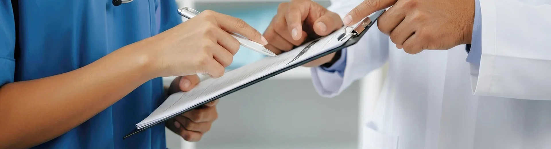 Two laboratory staff review a clipboard and discuss the information together.