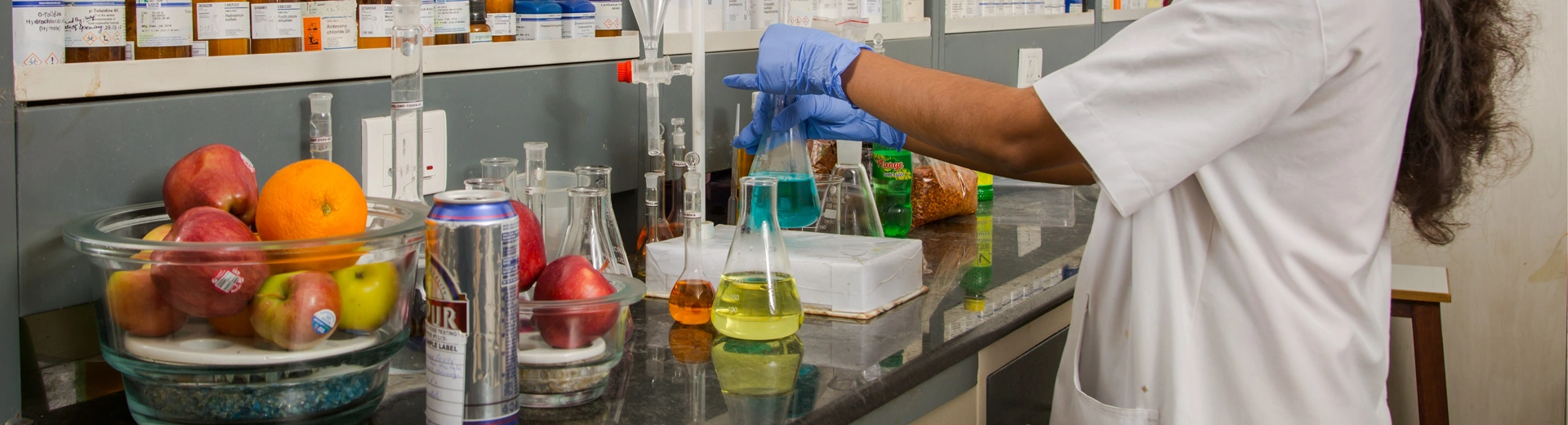 Laboratory worker tests food and beverage samples using liquid samples and glassware.