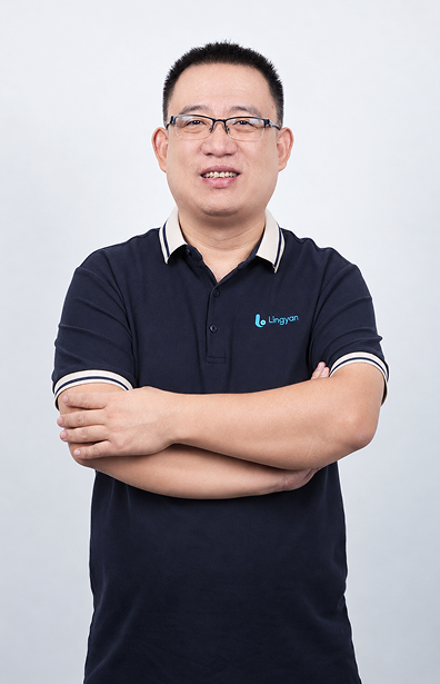Hugo wears a navy uniform and glasses, smiling with his arms crossed.
