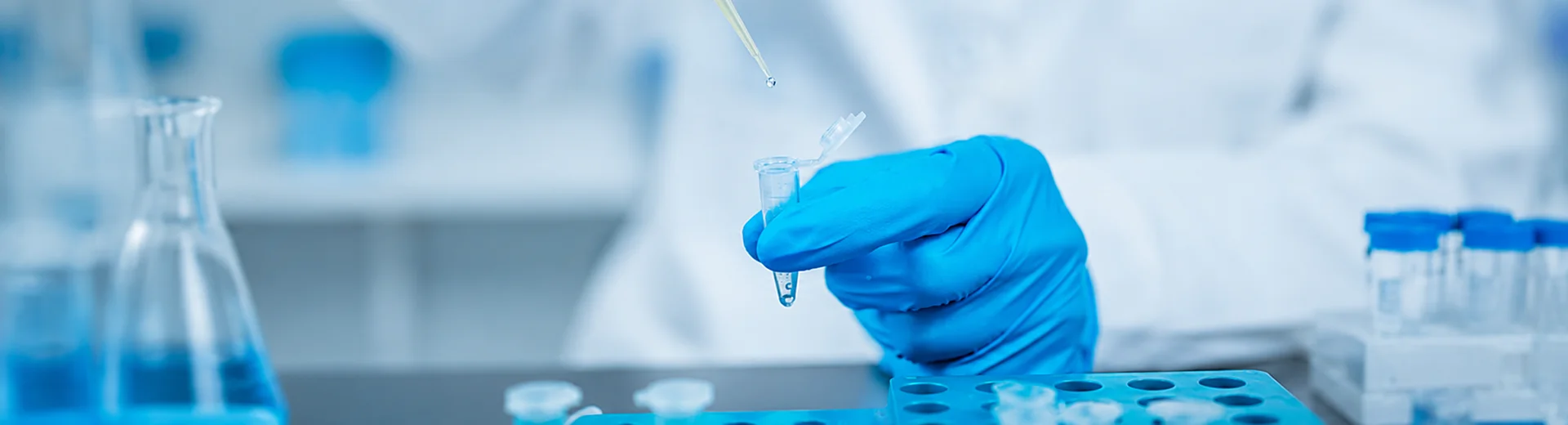 A laboratory technician uses a pipette to add liquid to a PCR tube.
