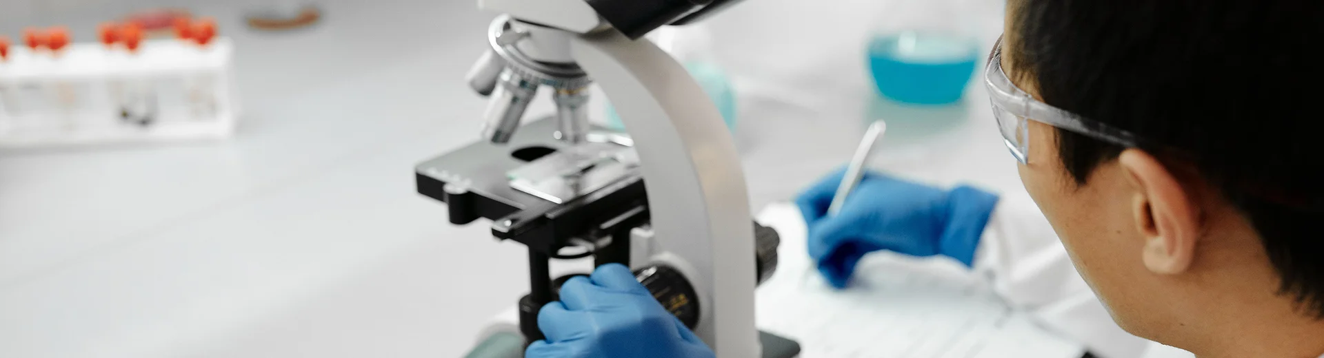 A laboratory technician uses a microscope to inspect samples for quality control.