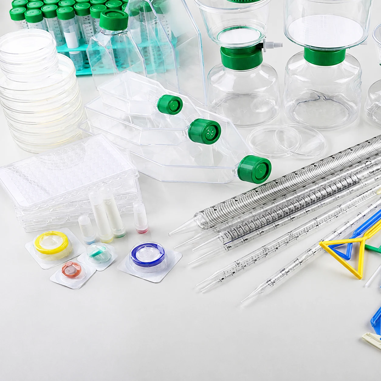 Laboratory bench with culture flasks, Petri dishes, filtration units, pipettes, and centrifuge tubes.