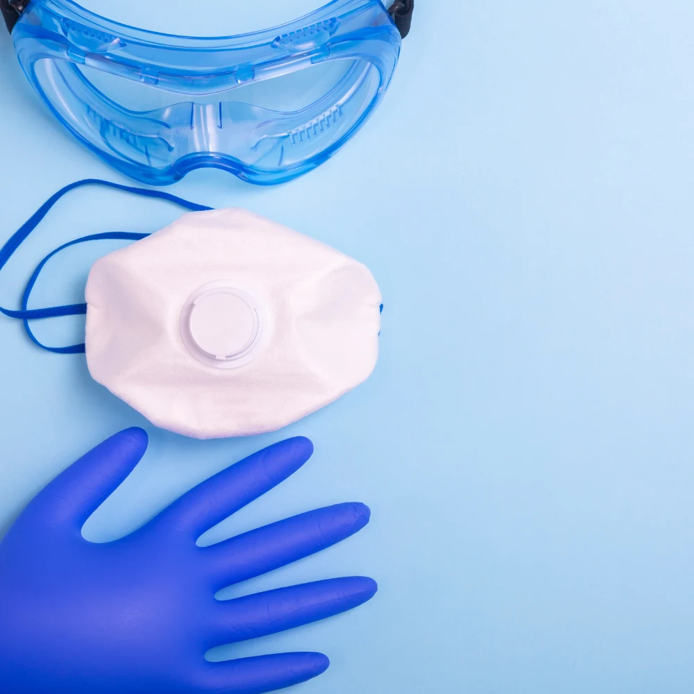 Blue protective gloves and a white face mask arranged on a clean laboratory surface.