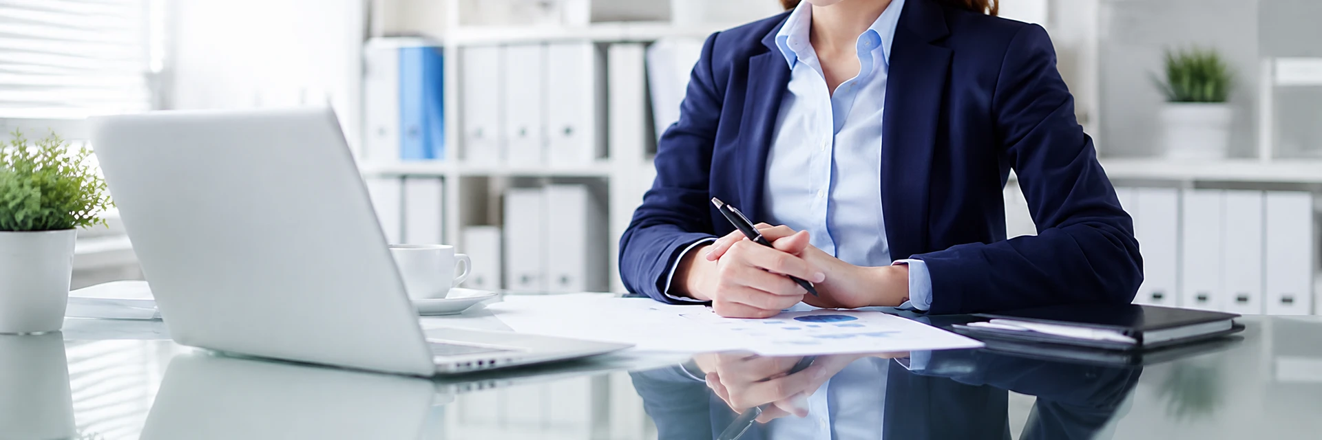 Staff use a computer at a desk with coffee and documents to record information and contact us.