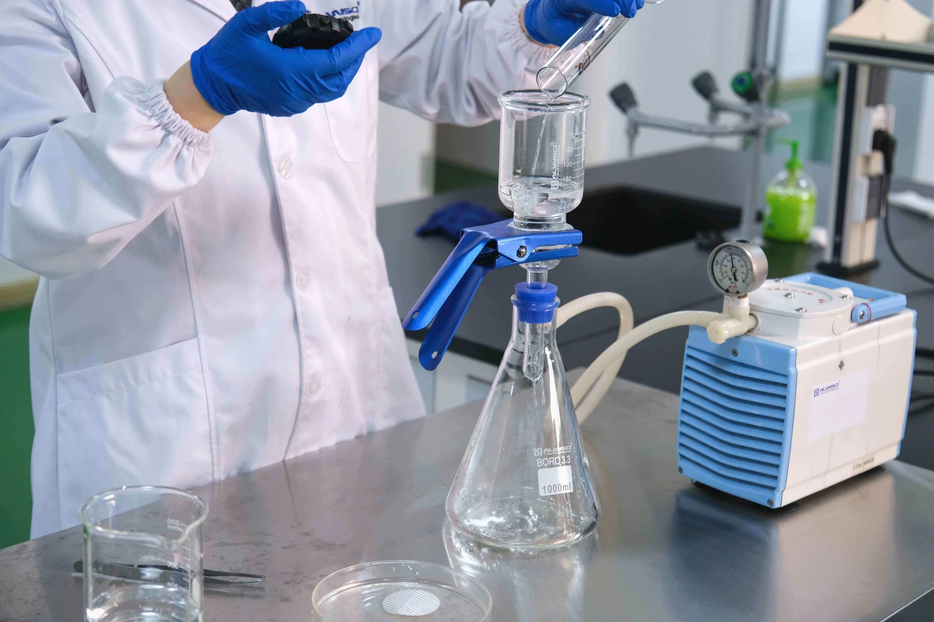 A researcher uses a graduated cylinder to add liquid to a vacuum filtration system.