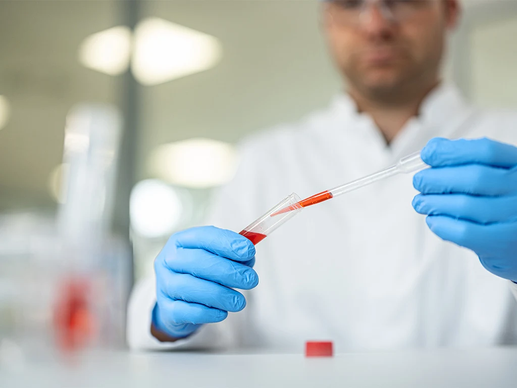 A researcher uses a Pasteur pipette for liquid transfer.