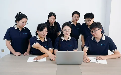 Colleagues gather around a laptop to discuss work.